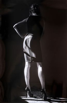 photographie en noir et blanc d'une femme en robe, debout dans une pièce