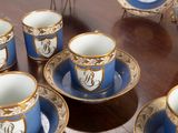several cups and saucers are sitting on a table with gold trimming