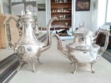 deux théières en argent posées sur une table dans un salon