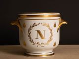 un vase blanc et doré sur lequel figure la lettre « n »