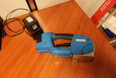 une agrafeuse bleue posée sur une table en bois, à côté d'un téléphone portable