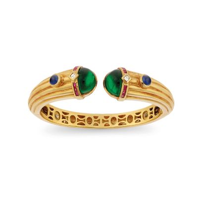 a close up of a yellow gold bracelet with green and blue stones