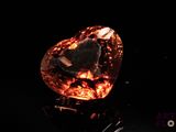 an orange diamond on a black surface with a black background