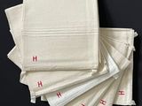 Plusieurs serviettes blanches ornées de lettres rouges sont empilées les unes sur les autres