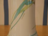 a white vase with a flower on it sitting on a table