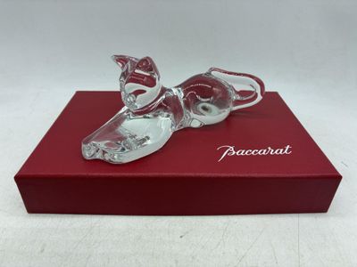 La figurine en verre représentant une paire de chaussures est posée sur une boîte rouge.