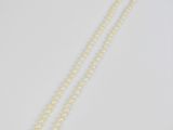 un collier de perles blanches avec un fermoir en or sur fond blanc