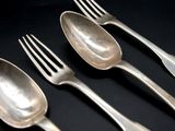 three silver spoons and a fork on a black surface