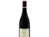 a bottle of red wine sitting on top of a white table
