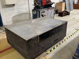 a table in the middle of a warehouse with a machine in the background