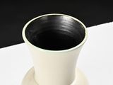 a black and white vase sitting on a white table