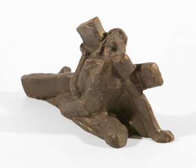 statue d'un homme portant une croix sur le dos, posée sur une surface blanche