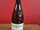 une bouteille de vin posée sur une table devant un mur rouge