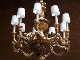 a gold chandelier with white lamps hanging from the ceiling