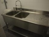 un lavabo en acier inoxydable équipé d'un robinet, situé dans des toilettes publiques