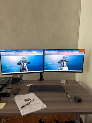 deux écrans d'ordinateur posés sur un bureau, avec un clavier et un ordinateur portable
