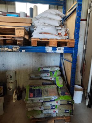 de nombreux sacs de ciment posés sur une étagère dans un entrepôt