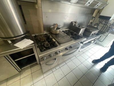 une personne debout dans une cuisine, à côté d'une cuisinière et d'un four
