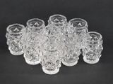 a set of twelve cut crystal glasses on a black background