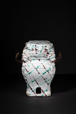 a white and green vase with a handle on a black background