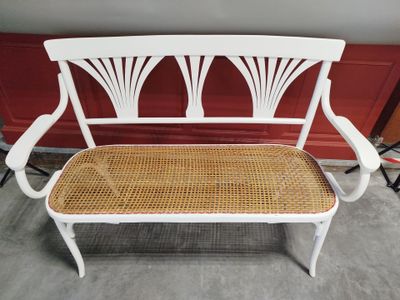 un banc blanc avec une assise en osier