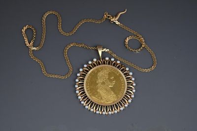 a close up of a necklace with a gold coin on a chain