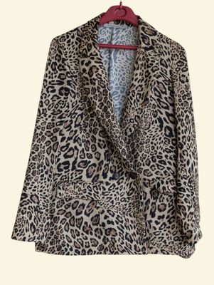 a leopard print jacket hanging on a hanger on a wall