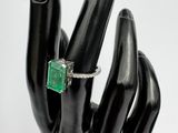 une main noire ornée d'une bague sertie d'une pierre verte