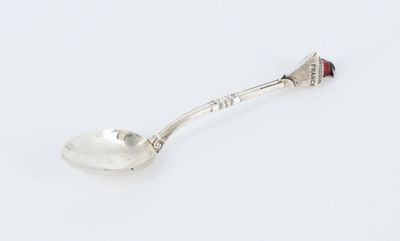cuillère en argent ornée d'une perle rouge, posée sur un fond blanc
