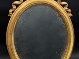 un miroir ancien dans un cadre doré, posé sur un socle en bois, avec un fond noir