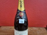 La bouteille de champagne est posée sur la table, devant un mur rouge.