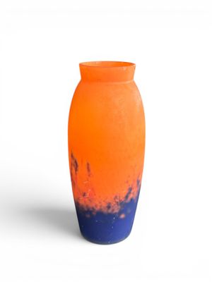 un vase orange et bleu posé sur une surface blanche