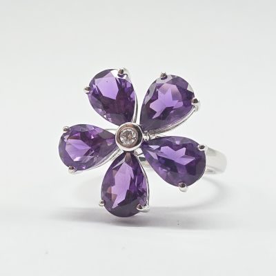 un gros plan d'une bague ornée de pierres violettes sur fond blanc