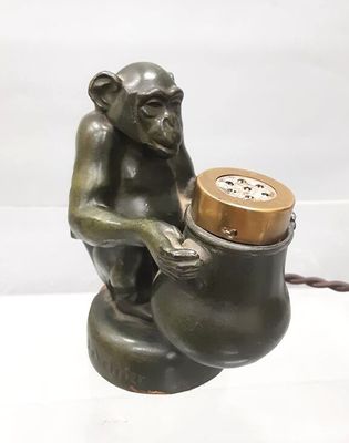 a statue of a monkey sitting on a pot with a clock in it