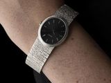 someone is wearing a watch on their wrist with a black background