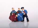 three figurines of people sitting on a bench