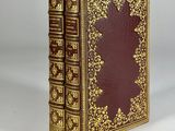 an old book with gold trimming and a red cover
