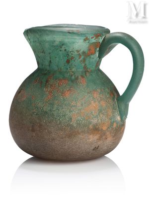 a green vase with a handle sitting on a white surface