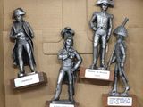 four statues of men in different poses in a cardboard box