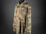 une veste militaire posée sur un mannequin, sur fond noir