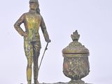 bronze figurine of a man holding a cane next to a urn