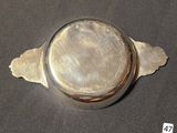 a silver plate with a leaf on it on a table