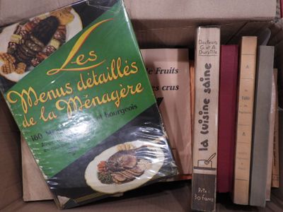 une boîte remplie de livres posée sur une table, à côté d'une pile de livres