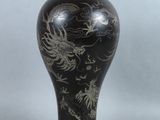 un vase noir orné d'un motif représentant un dragon