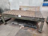 une table en métal percée de trous, au milieu d'une pièce