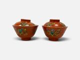 une paire de vases rouges ornés de motifs floraux sur fond blanc