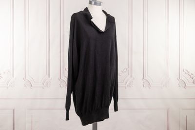 une robe-pull noire posée sur un mannequin devant un mur blanc
