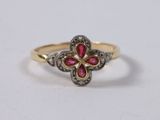 a yellow gold ring with a flower shaped ruby stone and diamonds