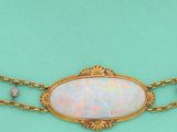 une image représentant un collier en or orné d'oplites sur fond turquoise
