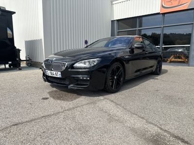 une BMW Série 6 noire garée devant un immeuble